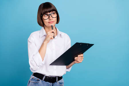 Portrait of attractive minded girl specialist writing list plan making decision isolated over bright blue color backgroundの写真素材