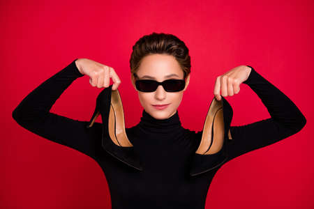 Photo of young attractive woman happy positive smile hold stilettoes wear eyeglasses isolated over...