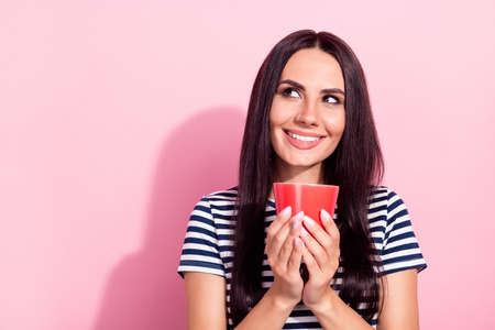 Photo of attractive charming young woman look empty space dream hold cup isolated on pink color backgroundの写真素材