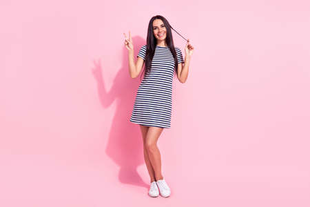 Full length body size photo of funky model showing v-sign gesture smiling isolated on pastel pink color backgroundの写真素材