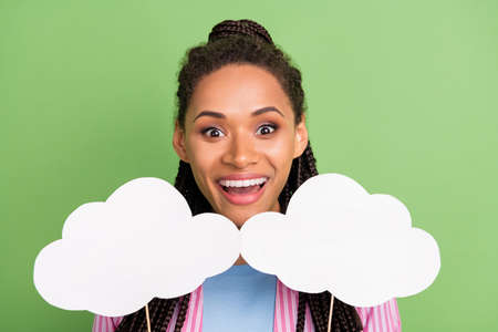 Photo of charming impressed dark skin woman dressed striped shirt holding two mind clouds empty...