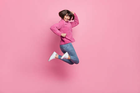 Full body photo of cheerful young happy pretty crazy woman jump up enjoy isolated on pink color backgroundの写真素材