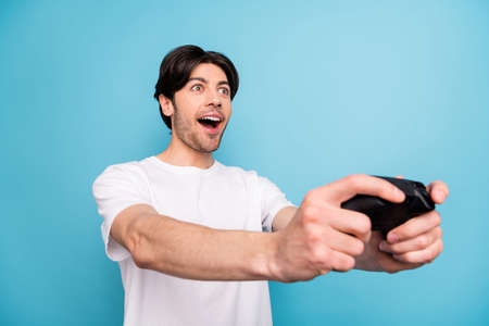 Portrait of attractive amazed cheerful guy playing video game having fun isolated over vibrant blue color backgroundの写真素材