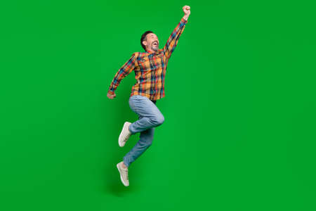 Full length body size view of attractive cheerful man jumping striving isolated over bright green color backgroundの写真素材