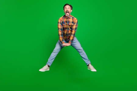 Full length body size view of attractive cheerful man jumping having fun fooling isolated over bright green color backgroundの写真素材