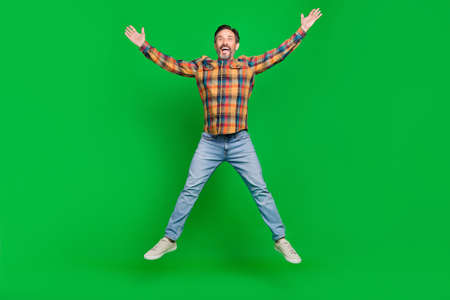 Full length body size view of attractive cheerful man jumping having fun good mood isolated over bright green color backgroundの写真素材