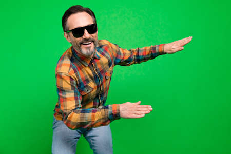 Portrait of attractive funky cheerful man dancing having fun good mood rest isolated over bright green color backgroundの写真素材