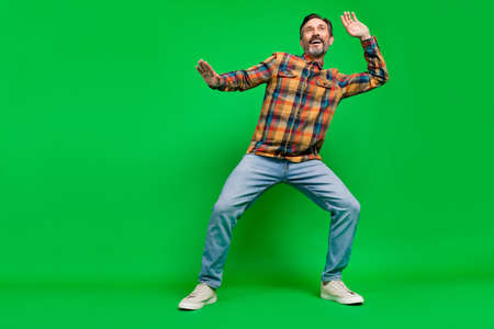 Full length body size view of attractive cheerful man dancing having fun chill out clubbing isolated over bright green color backgroundの写真素材