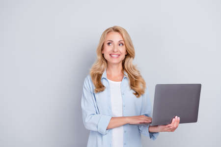 Photo of curious freelancer lady hold laptop look empty space wear blue shirt isolated grey color backgroundの写真素材