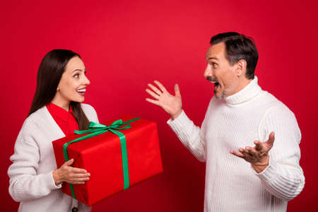 Photo of stylish trendy man and woman husband wife surprised gift give holiday isolated on red color backgroundの写真素材