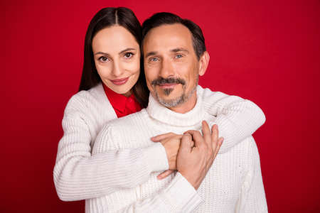 Photo of cheerful man and woman husband wife couple hug enjoy good mood isolated on red color backgroundの写真素材