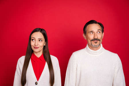 Photo of dreamy positive mature man and woman couple christmas look empty space isolated on red color backgroundの写真素材