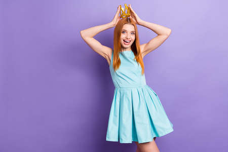 Photo of amazed young happy pretty woman hold hands place head crown isolated on purple color backgroundの写真素材