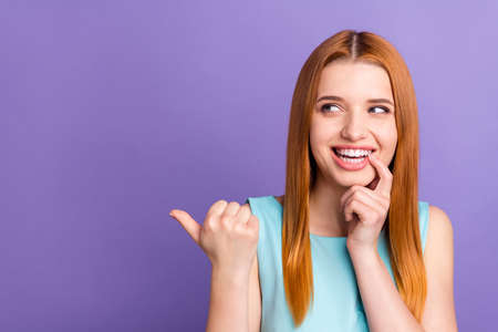 Photo of charming young happy lady look bite nail empty space minded isolated on violet color backgroundの写真素材