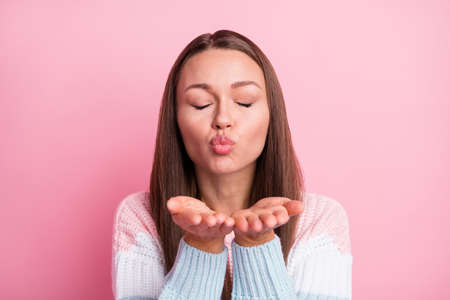 Photo portrait of happy girlfriend sending air kiss pouted lips closed eyes isolated on pastel pink color backgroundの写真素材