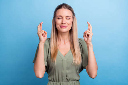 Photo of dreamy exciting young woman dressed green clothes closed eyes fingers crossed smiling...