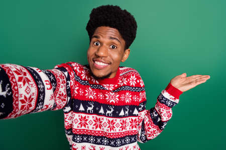 Photo of promoter guy make selfie hand demonstrate empty space wear print sweater isolated green color backgroundの写真素材