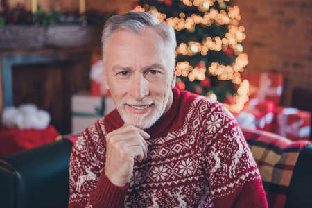 Photo portrait senior man smiling wearing sweater sitting on couch thoughtfulの写真素材