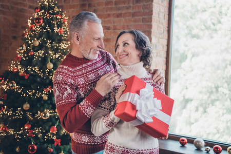 Photo portrait elder couple celebrating holidays husband giving present to his wife on new yearの写真素材
