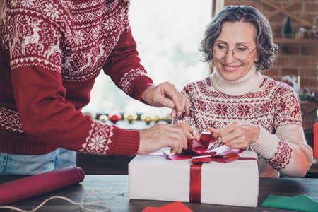 Cropped photo of cheerful positive couple prepare wrap box presents bow wear ornament pullover home indoorsの写真素材