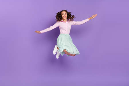 Full size photo of cool young brunette lady jump wear shirt skirt footwear isolated on violet backgroundの写真素材