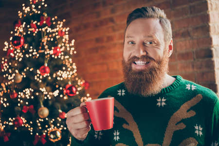 Photo of positive excited happy young man hold hands coffee tree christmas holiday indoors inside...