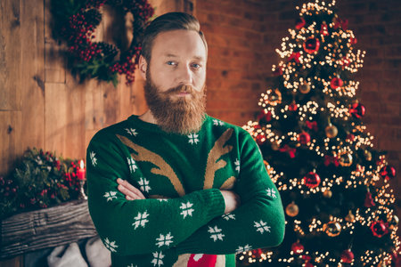 Portrait of attractive serious guy folded arms festal decorated room at modern loft industrial style indoorsの写真素材
