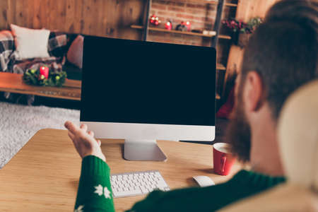 Rear back view photo of friendly sociable guy look pc screen empty space wear sweater decorated office indoorsの写真素材