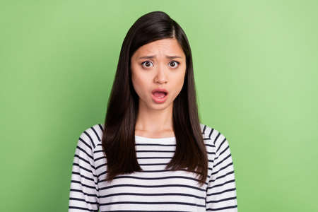 Photo of scared brunette young lady open mouth wear striped shirt isolated on green color backgroundの写真素材
