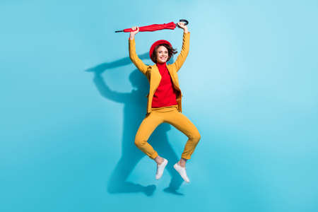 Full length photo of young girl happy positive smile have fun jump fly parasol isolated over blue color backgroundの写真素材