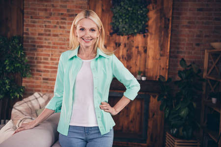 Photo of positive happy charming pretty old woman hold hand waist smile indoors inside house home flatの写真素材