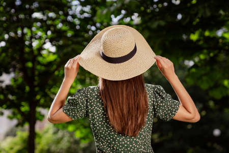 Rear back view photo of charming woman wear green dotted dress straw headwear nature park garden outdoorsの写真素材