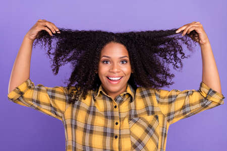 Photo of cheerful amazed lady raise hands touch hair wear plaid shirt isolated violet color backgroundの写真素材