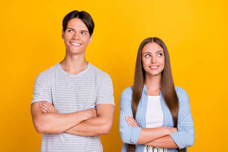 Portrait of attractive cheery pensive couple folded arms pondering copy space isolated over bright yellow color backgroundの写真素材