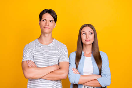 Portrait of attractive cheery minded couple partners folded arms contemplate isolated over bright yellow color backgroundの写真素材