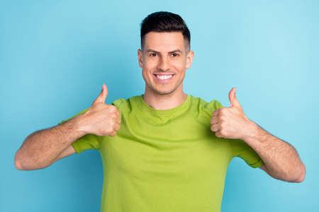 Photo portrait man in green t-shirt showing thumb up like gesture recommend happy isolated pastel...