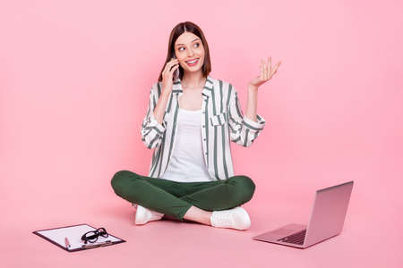 Full size photo of young girl happy positive smile call talk cellphone conversation sit floor isolated over pastel color backgroundの写真素材