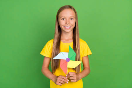 Portrait of attractive cheerful long-haired girl holding fan eco energy isolated over vibrant green color backgroundの写真素材