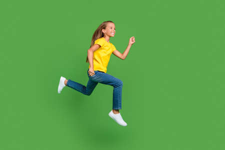 Full length body size view of attractive cheerful girl jumping running active life isolated over bright green color backgroundの写真素材