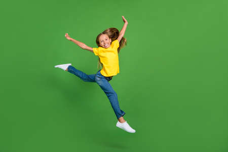 Full length body size view of attractive cheerful girl jumping dancing twine running isolated over vivid green color backgroundの写真素材
