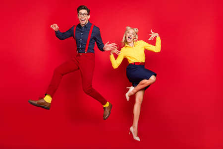 Full length body size view of attractive cheerful couple jumping fooling dancing jive lindy isolated over bright red color backgroundの写真素材