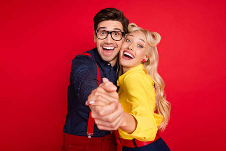 Photo of funky beautiful young guy lady wear pin up clothes dancing rock and roll smiling isolated red color backgroundの写真素材
