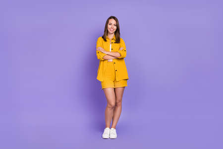 Full length photo of funky young brunette lady crossed arms wear yellow suit sneakers isolated on violet backgroundの写真素材