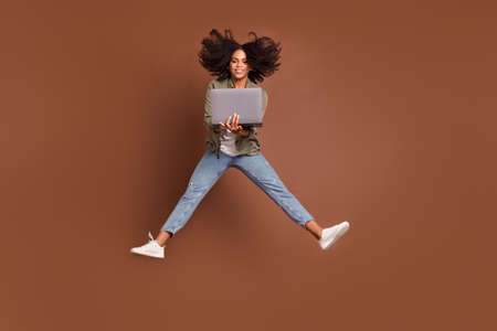 Full size portrait of carefree energetic active lady hold netbook have good mood isolated on brown...