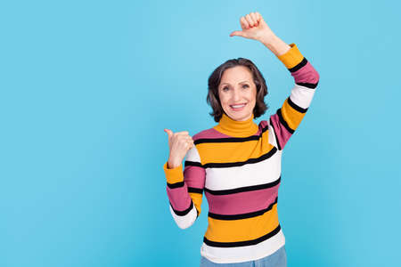 Photo of impressed grey hairdo elder lady index empty space wear striped pullover isolated on blue...