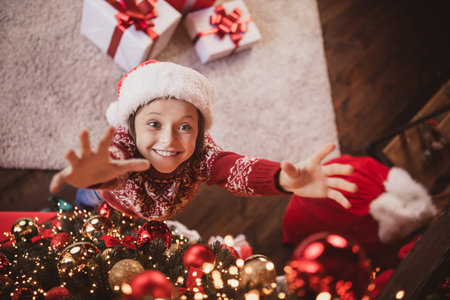 Photo of charming cute school girl wear print pullover headwear smiling hanging new year balls indoors house home roomの写真素材