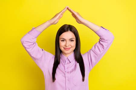 Photo of optimistic brown hairdo young lady hold arms up wear purple shirt isolated on yellow color backgroundの写真素材