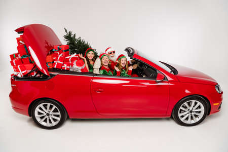 Photo of charming pretty santa claus helpers riding car delivering presents isolated white color...