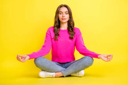 Full size photo of young attractive beautiful relaxed peaceful girl sitting floor doing yoga isolated on yellow color backgroundの写真素材