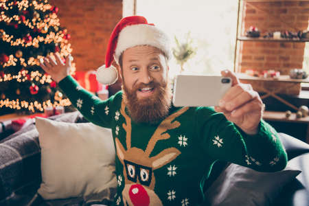 Portrait of attractive cheerful guy using gadget taking selfie blogging congratulating at modern...